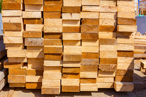 Yellow wooden chopped planks arranged in a row placed at the alfresco on the construction site.