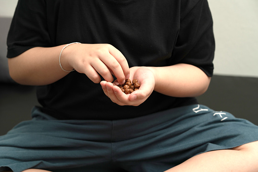 kid hand hold chocolate cereal ball shape for eating breakfast