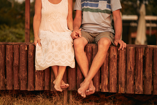 Senior couple enjoying sunrise on a beach vacation. Close-up of their legs. Active seniors. Unrecognizable people.