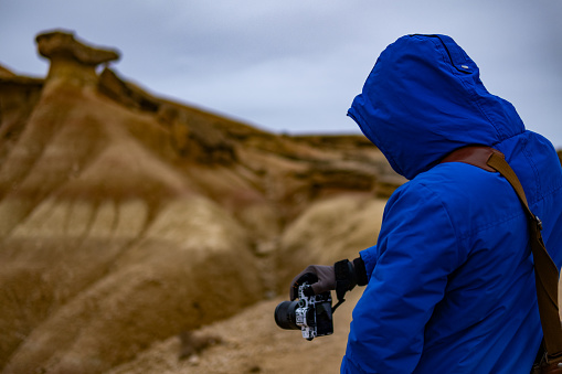 A young boy is taking a photograph of a mountain in the Bárdenas Reales, Navarra, Spain.
