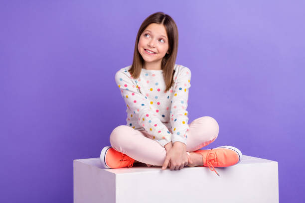 istock Photo of adorable dreamy little girl dressed dotted pullover sitting cube looking empty space isolated purple color background 1688630636