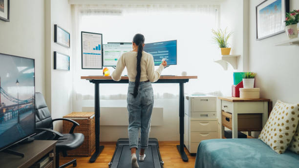 istock Woman working at standing desk is using credit card while walking at treadmill 1688652346