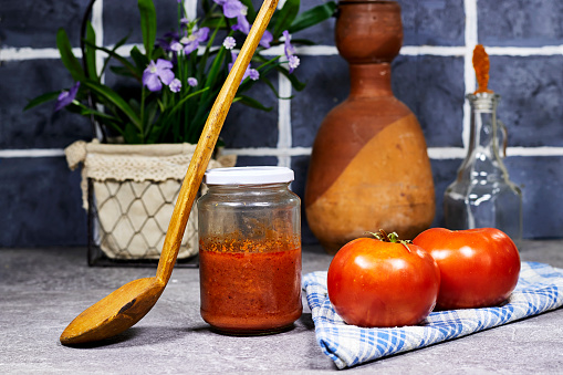 istock tomato sauce in glass bottle with wooden spoon and flowers pot near tile wall 1688653998