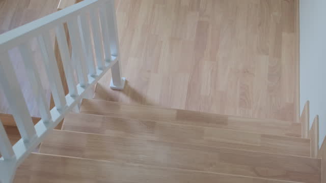 Going down on stairs with wood banister.