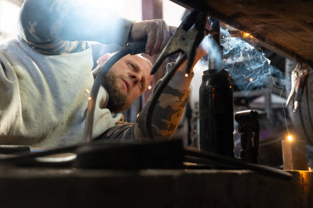 the professional auto mechanic uses a welding machine to repair a car. - car bodywork flash imagens e fotografias de stock