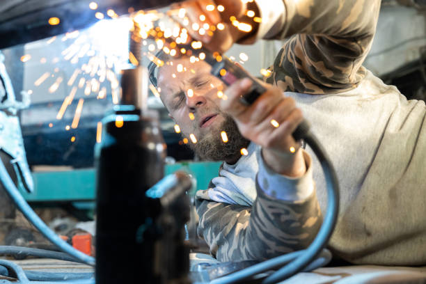 the professional auto mechanic uses a welding machine to repair a car. - car bodywork flash imagens e fotografias de stock