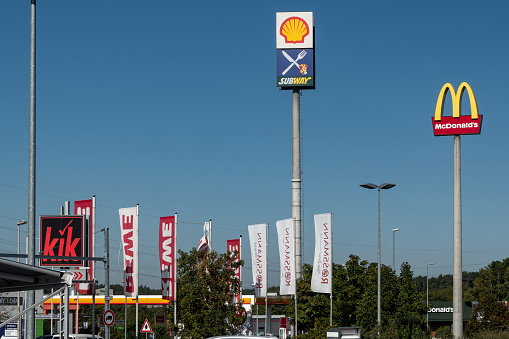 Wernberg-Köblitz, Germany - September 8, 2023: Advertising in the commercial area on the A 93 motorway, exit 27 Wernberg-Köblitz. Brand names represented there include McDonalds, Shell, Subway, REWE, kik, Rossmann. Sunny september morning with clear blue sky.