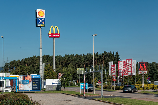 Wernberg-Köblitz, Germany - September 8, 2023: Advertising in the commercial area on the A 93 motorway, exit 27 Wernberg-Köblitz. Brand names represented there include McDonalds, Shell, Subway, REWE, kik, Conrad, Rossmann. Sunny september morning with clear blue sky.