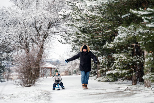 отец и маленький сын играют с санками в снежный день - little boys sled clothing slide стоковые фото и изображения