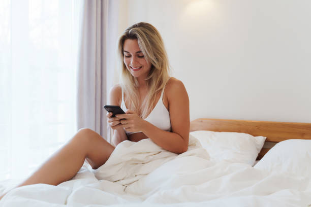 istock Young blonde woman browsing on smartphone in bed during morning hours 1688753953