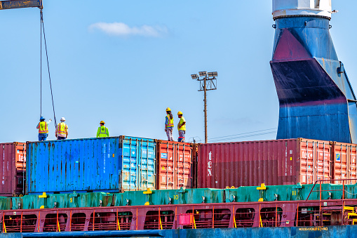 Container cargo freight ship during discharging at industrial port move to container yard by trucks, handlers, cargo plane, copy space, logistic import export background and transport industry concept