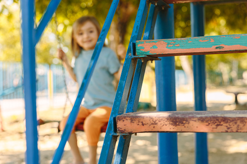 Blurred picture of a beautiful little girl swinging at her favorite playground. Selective focus. High quality photo