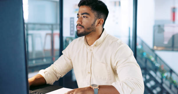 istock Computer, research and businessman working on a project, report or website in an office. Technology, professional and Indian male employee typing company proposal with a deadline in the workplace 1688785791