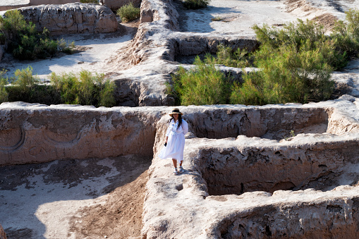 Lady wearing a white dress and a hat is exploring the Ayaz Kala fortress, Uzbekistan