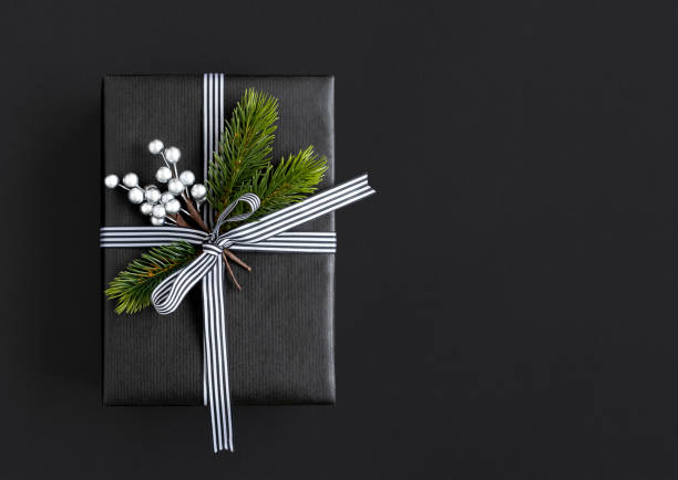 istock Black gift box with ribbon, spruce branches and silver berries with copyspace 1688809510