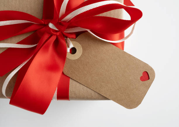 Empty brown gift tag on the box with red and white ribbon. Space for your text.