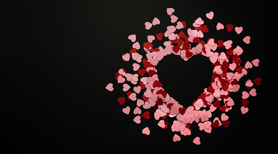 Banner with heart made of small paper red and pink hearts. Copyspace, black background. Valentine's Day card