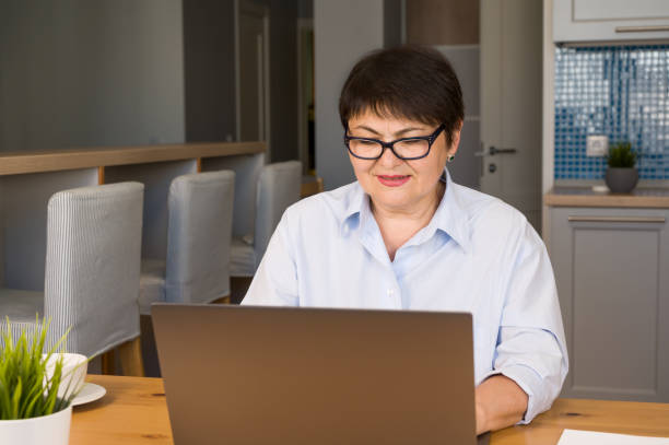 istock Front view on smiling senior woman using laptop application fro communication,talking,online shopping and learning 1688837898