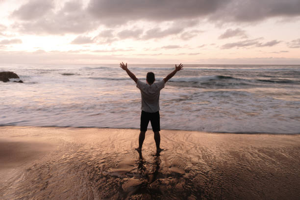 istock Man with arms raised at a beach at sunset 1688851268