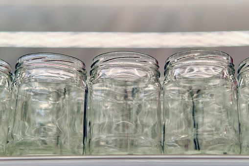 Empty glass jars in a row on the shelf in the kitchen.