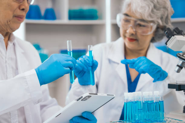 istock Senior scientists analyzing pharmaceuticals, asian people, senior man and woman, experienced experts in science, conducting pharmaceutical research in modern lab setting with powerful microscope. 1688864253