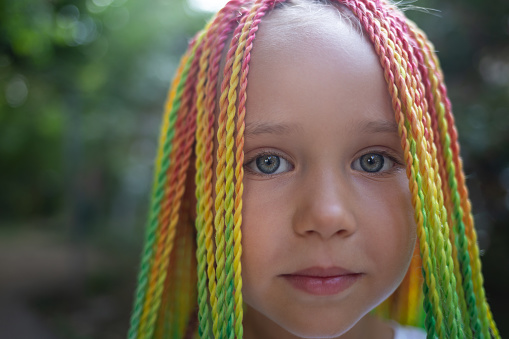 portrait of a little beautiful girl with multi-colored pigtails.