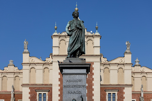 Krakow, Poland - September 6, 2023: Adam Mickiewicz Monument in front of renaissance medieval Cloth Hall (Sukiennice) located at Main Square in the Old Town