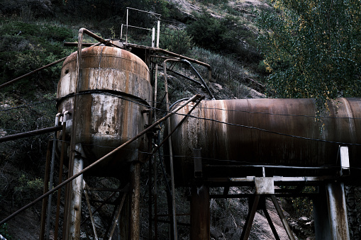 Old rusty water storage tanks on mountain river