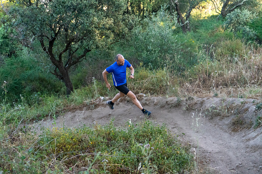 Middle-aged bald trail runner in action.