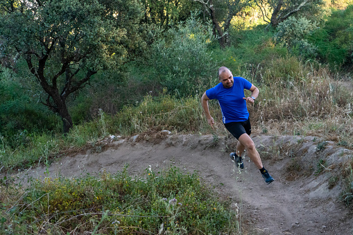 Middle-aged bald trail runner in action.