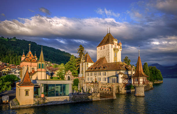 castelo à luz quente do pôr-do-sol - lake thun switzerland night lake - fotografias e filmes do acervo