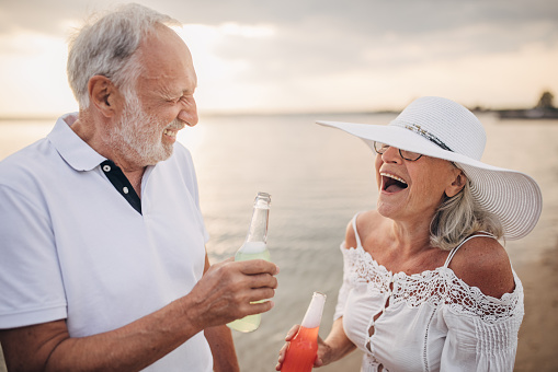 Man and woman, happy senior couple enjoying on the beach by the sea together.