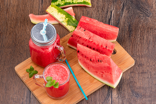 Ripe sliced watermelon and watermelon smoothie in a glass and jar with a lid and straw. Copy space.