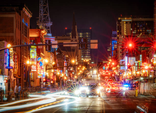 Lower Broadway, the focus of Nashville's central music district at nigiht, with bright lights from traffic and street lights, as well as the neon signs advertising the city's famous music bars.