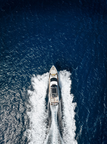 Aerial top view of a luxury yacht cruising with high speed over blue ocean