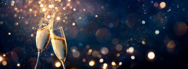 シャンパントーストのお祝い – 新年あけましておめでとうございます – 青の抽象的背景に金色の輝きを持つフルートと焦点の合っていないボケライト - シャンパン ストックフォトと画像