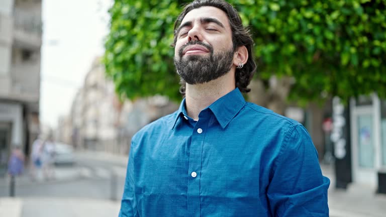 Young hispanic man smiling confident breathing at street