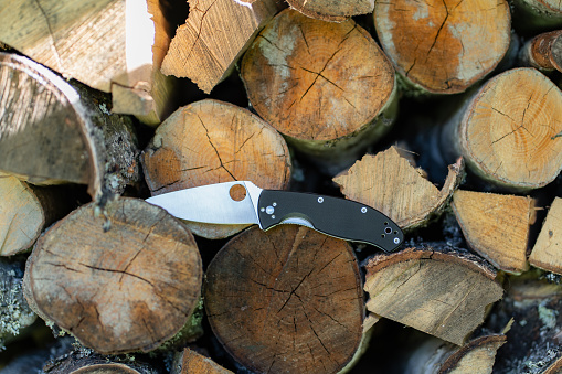 Folding knife next to firewood, survival knife. High quality photo