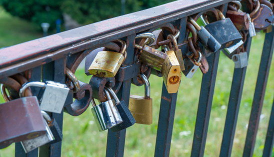 Many padlocks closed on a bridge and defocused background - love concept.
