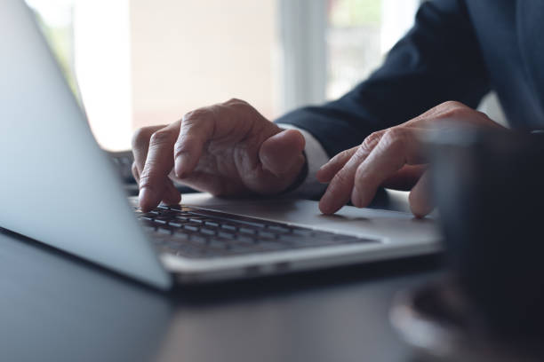 istock Businessman online working on laptop computer, surfing the internet, networking at modern office, closeup. Business man hand typing ob laptop computer keyboard on office desk 1689003158