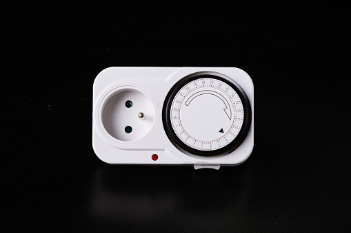 A set of sockets with a timer for lighting power control on a black background.