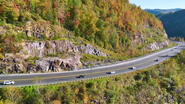 Aerial view of highway road in North Carolina through Appalachian mountains in golden fall season with fast moving trucks and cars. Interstate transportation concept