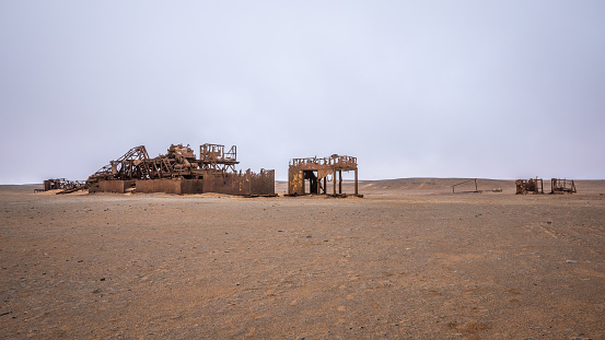 The rusted remains of an abandoned oil drilling rig between Henties Bay and Torra Bay, Skeleton Coast, Namibia.  Horizontal.
