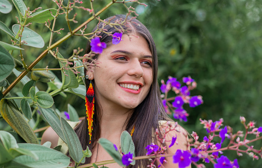 portrait of pretty woman smiling and looking to the side while standing in the middle of lilac flowers