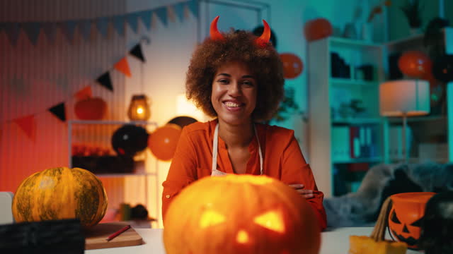 Portrait of a beautiful African American woman holding carved Halloween pumpkin