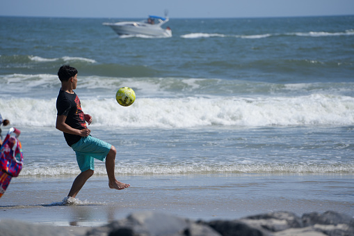 A teenage boy dribbles a soccer ball in the waves of Atlantic City, NJ on September 15th, 2023