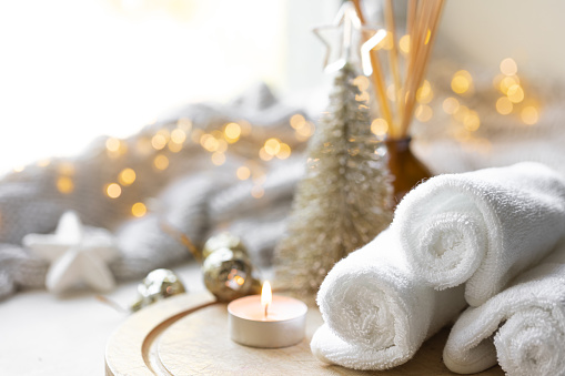 Christmas spa composition with towels and candles on a blurred background with bokeh lights, copy space.