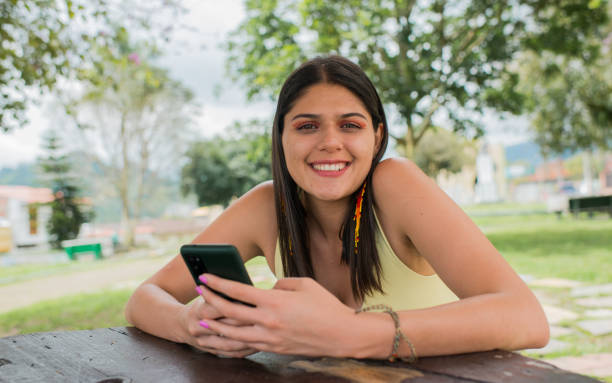 istock young woman smiling with her cell phone in her hands 1689052991