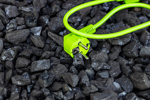 Green cable lying in a coal heap, concept, sustainable energy