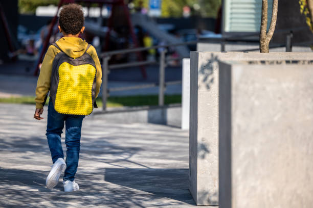 istock Curly-haired schoolboy with a backpack walking in the street 1689066790